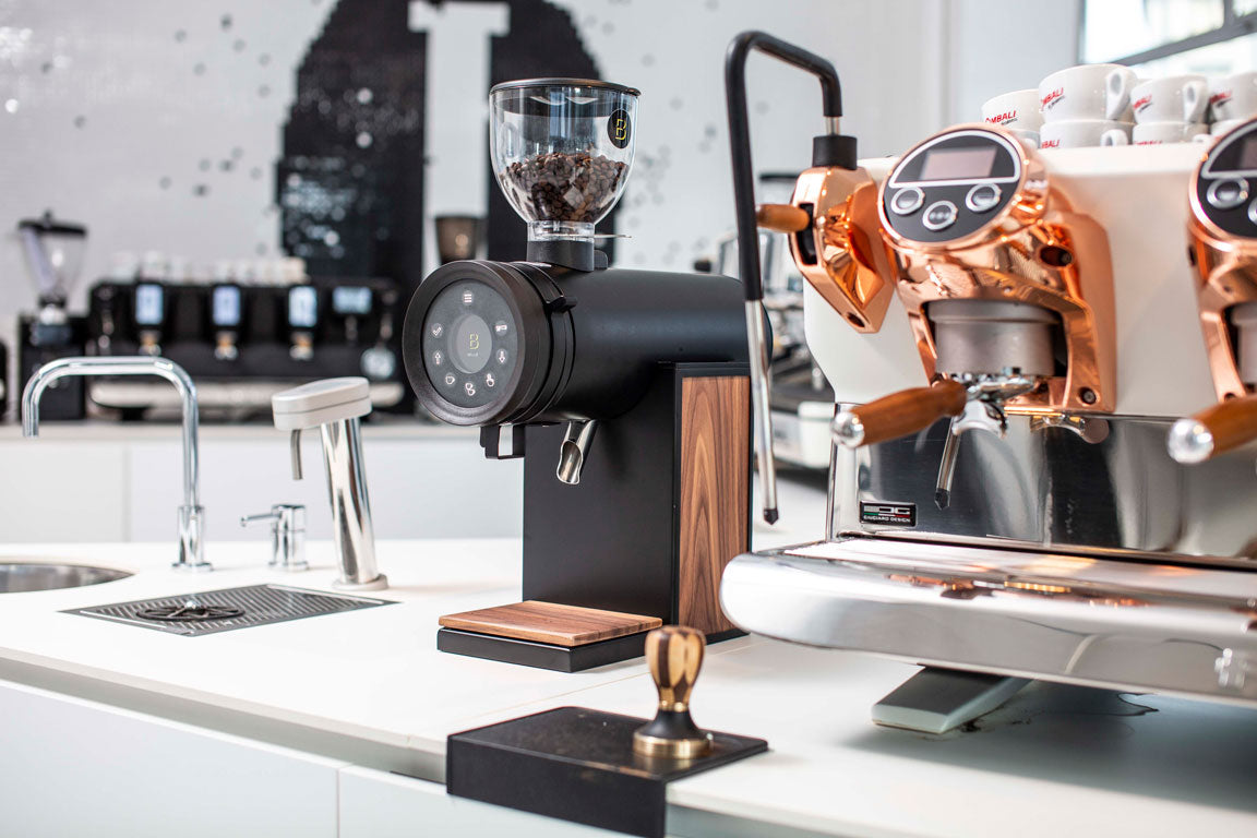 bentwood kaffekværn i kaffebar setup med espressomaskine ved siden af 