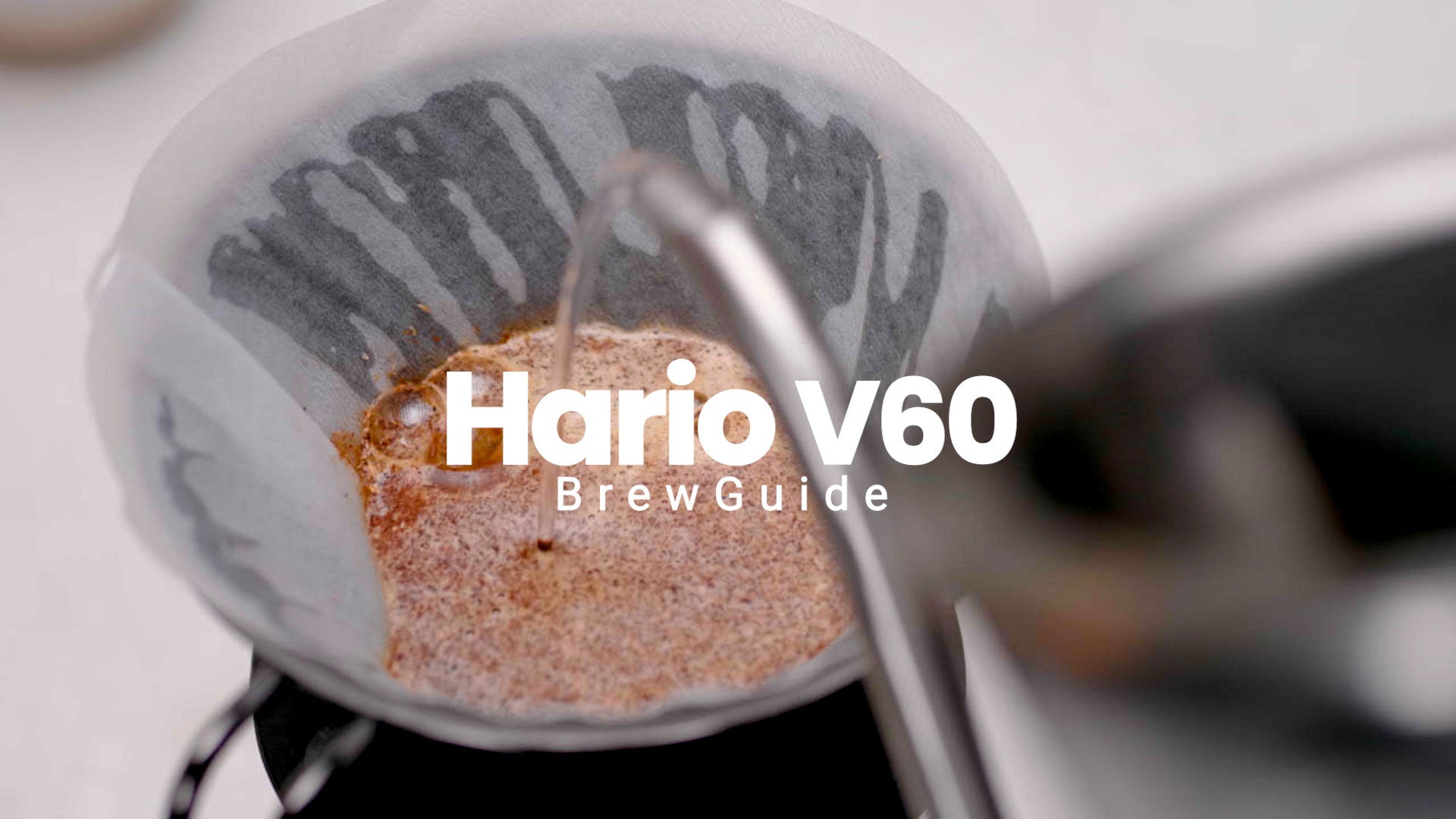 Billede af kaffe, der brygges med teksten "Hario V60 Brew Guide" i forgrunden.